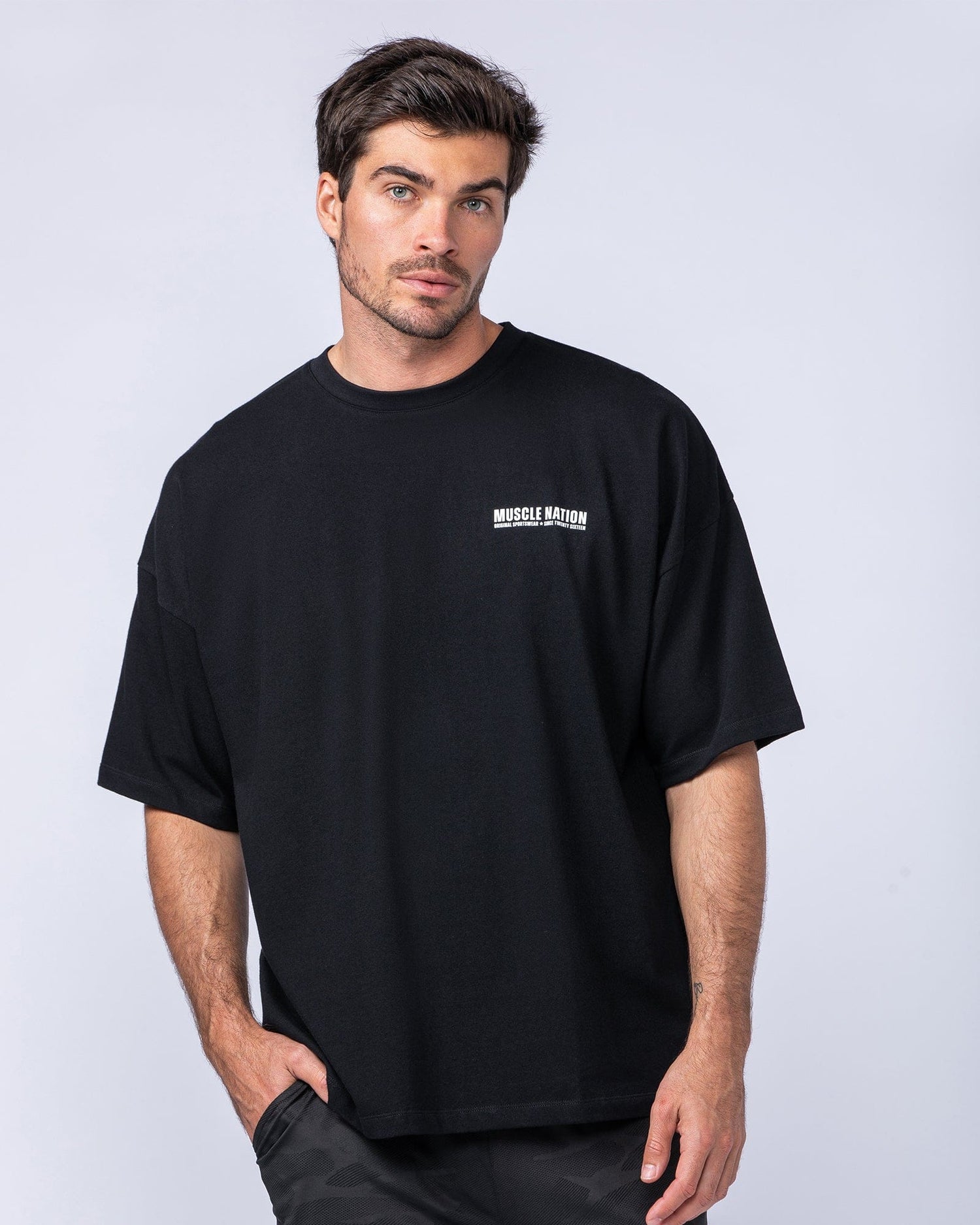 Male model wearing the black Original Oversized Boxy Tee, front view - heavyweight cotton tee with MN Original chest print